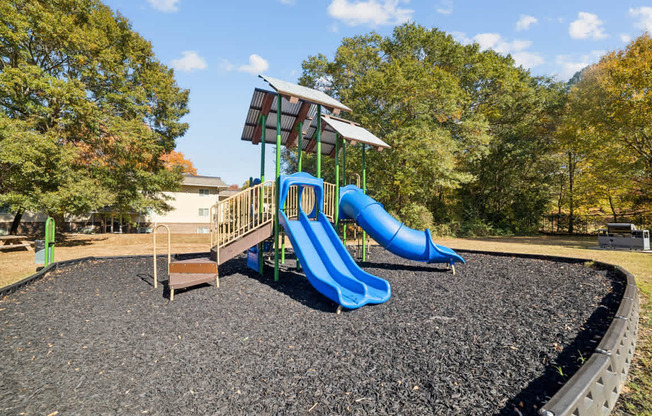 A playground with a blue slide and a green roofed structure.