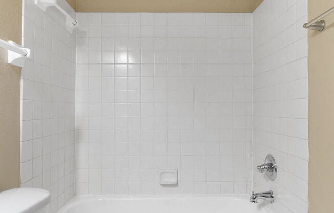 a white bathroom with a toilet and a tub