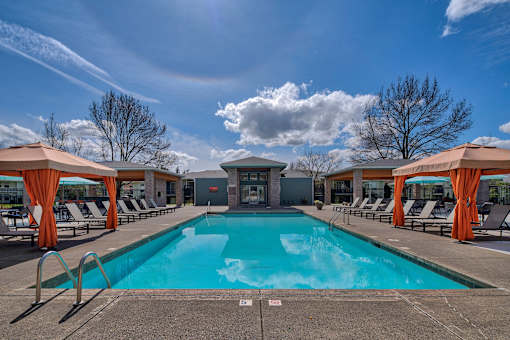A large swimming pool surrounded by lounge chairs and umbrellas.