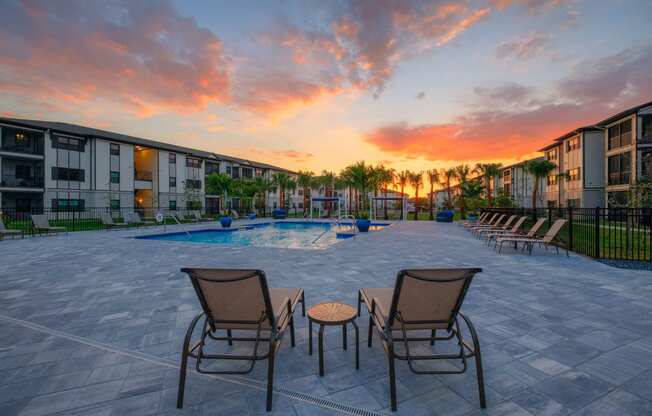 an outdoor patio area with chairs and a pool at sunset