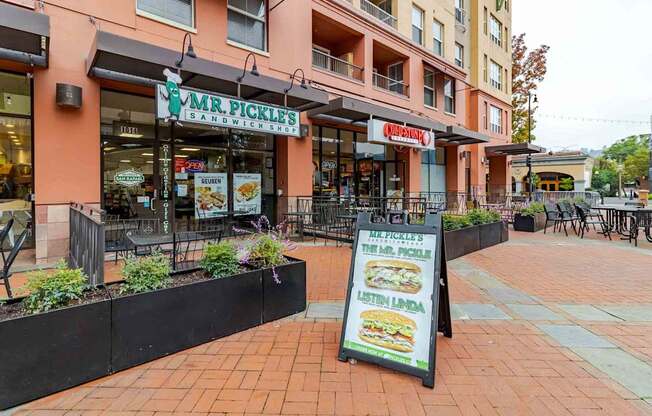 A sign for Mr. Pickle's Sandwiches is on a stand in front of a restaurant.