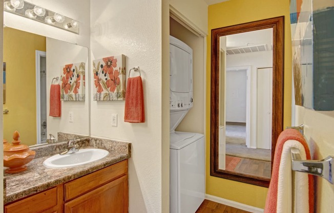 a bathroom with a sink and a mirror next to a washer and dryer