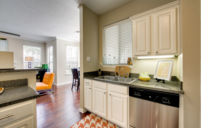 View of Upgraded Apartment Interior, Showing Kitchen with Plank Wood Flooring, View of Dining Area and Living Room at Stonebriar of Frisco Apartments