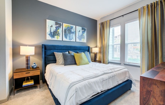 a blue and white bed in a bedroom with windows