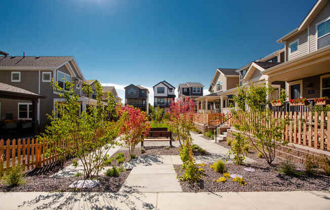 a group of houses with a walkway and benches in a garden