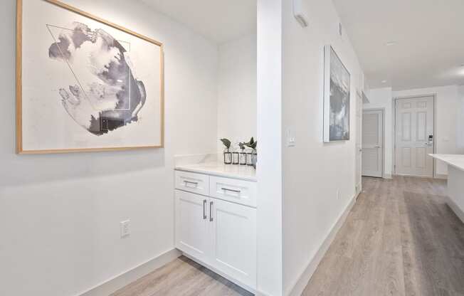 a kitchen with white cabinets and a painting on the wall