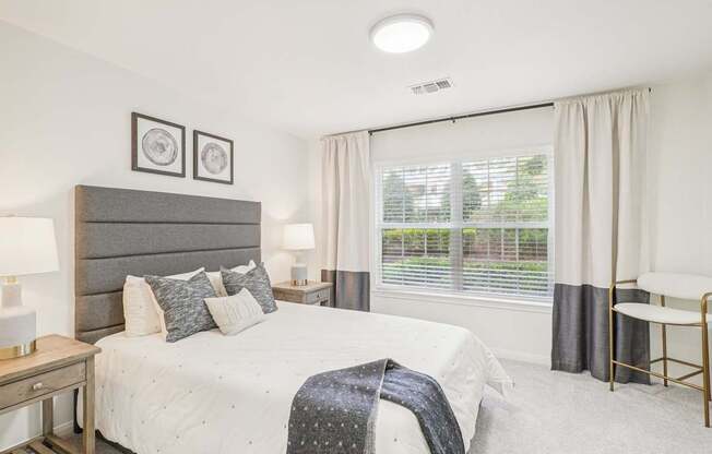 A bedroom with a large bed and a window with curtains.
