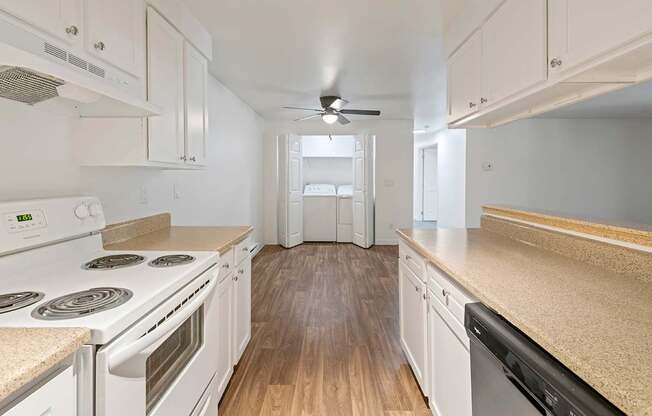 A kitchen with white appliances and wooden floors.