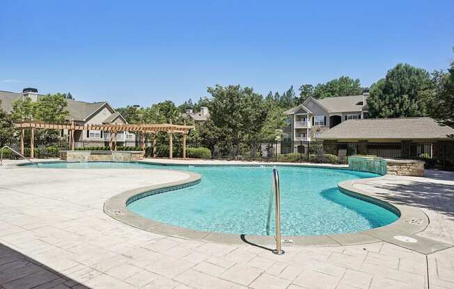 A large outdoor swimming pool surrounded by a stone patio.