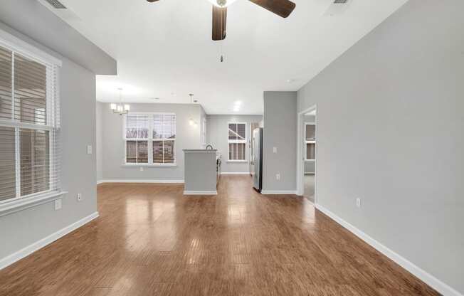 an empty living room with wood floors and a ceiling fan