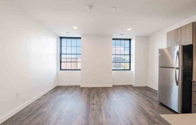 an empty living room with a refrigerator and a window