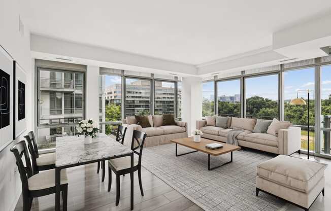 a living room with couches and a table with chairs and large windows