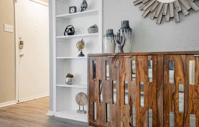 a living room with a wooden cabinet and a mirror on the wall