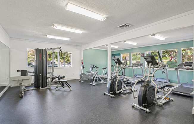 A gym with a variety of equipment including treadmills, stationary bikes, and weight machines.