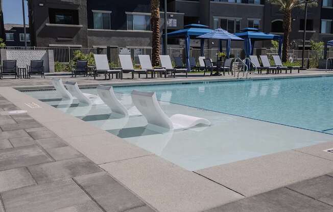 A pool with a blue umbrella and chairs.