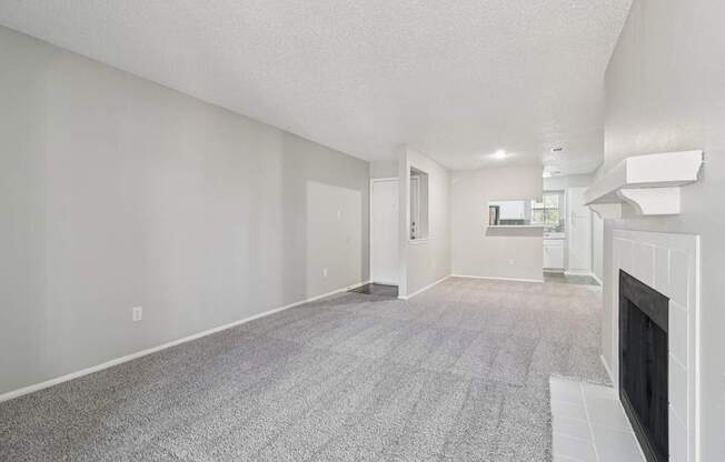 A living room with a fireplace and a grey carpet.