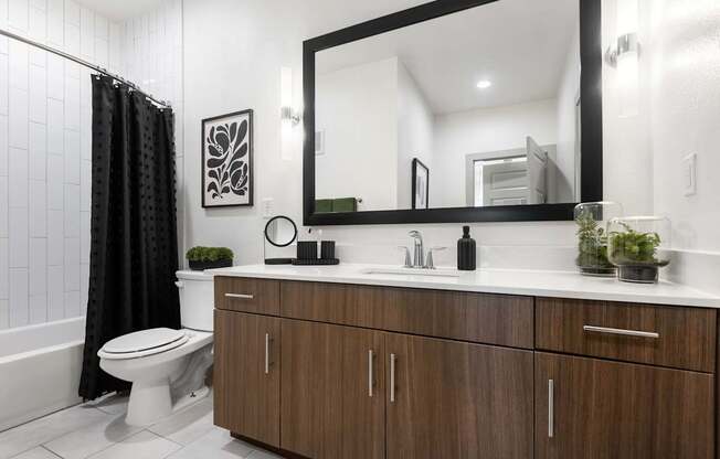 Updated Bathroom Featuring Wide Mirror, Tub, and Chrome Fixtures