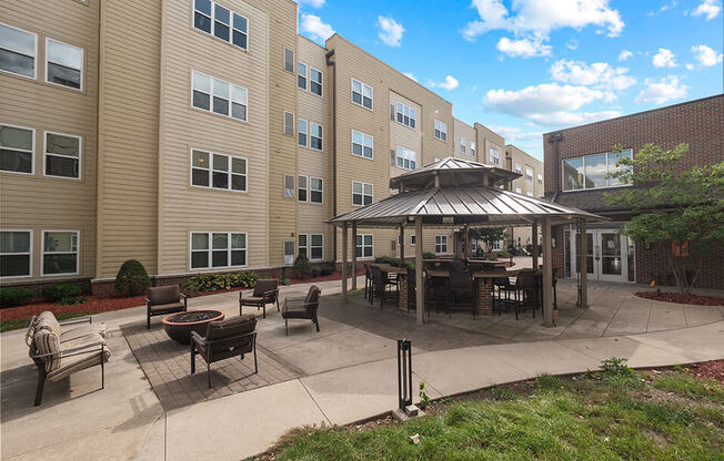 an outdoor patio with a firepit and gazebo in front of an apartment building