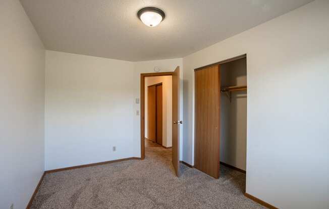 a bedroom with carpeted flooring and a door to a closet. Fargo, ND Southview Village Apartments