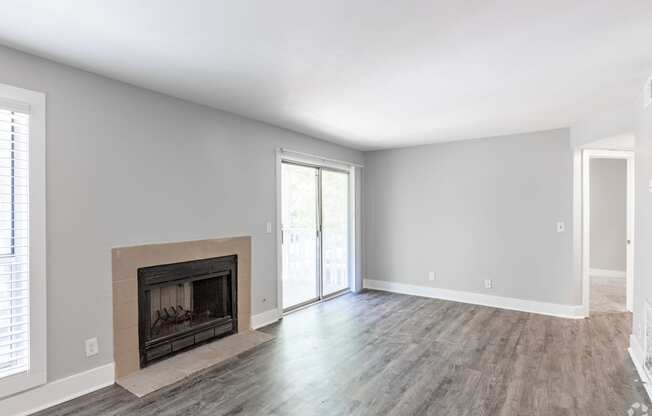 an empty living room with a fireplace and a sliding glass door
