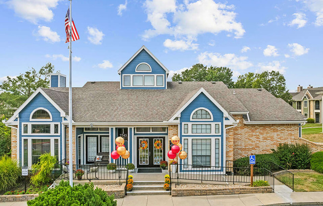 the front of a house with balloons and an flag