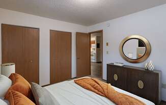 a bedroom with a bed and a dresser and a mirror. Fargo, ND Parkwood East and West Apartments