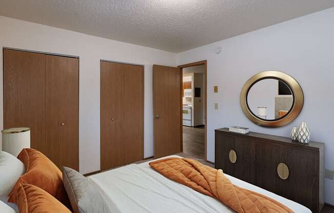 a bedroom with a bed and a dresser and a mirror. Fargo, ND Parkwood East and West Apartments