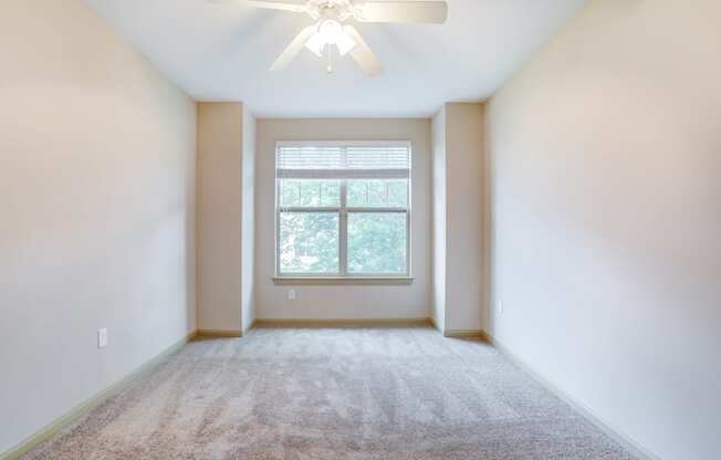 an empty room with a ceiling fan and a window