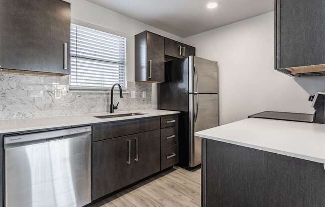 A modern kitchen with dark wood cabinets and stainless steel appliances.