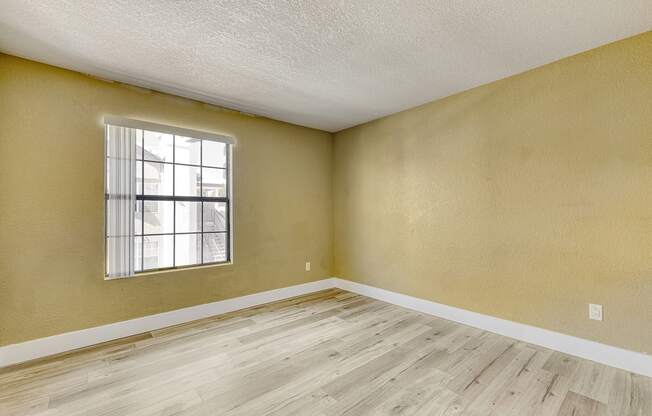 an empty living room with wood floors and a window