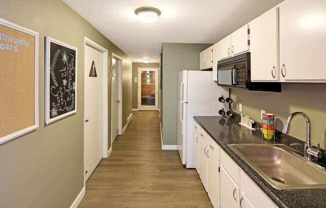 a kitchen with white cabinets and a sink and a refrigerator