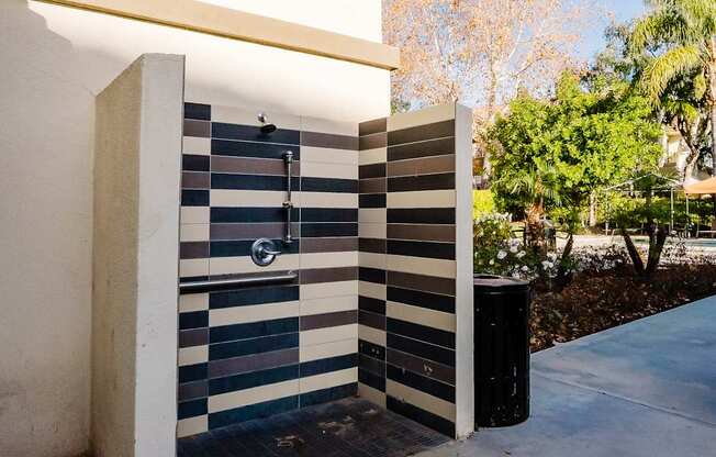 A shower with a black and white tiled wall.