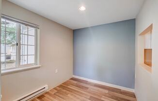 a bedroom with a large window and hardwood floors