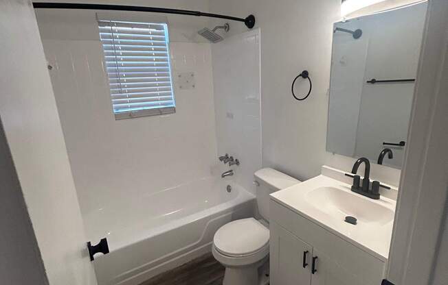 A bathroom with a toilet, sink, and a window.