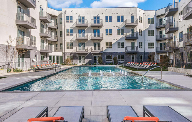 Sparkling resort style swimming pool with cushioned lounge chairs