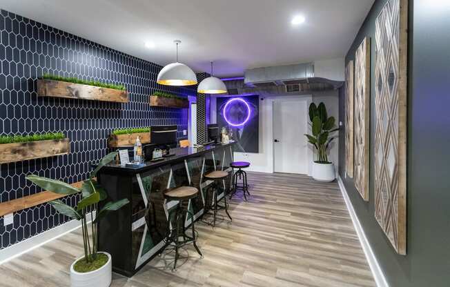 a room with a bar and stools in front of a black tiled wall with a
