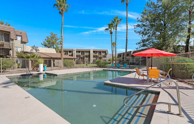 our apartments have a resort style pool with chairs and an umbrella in Tucson.