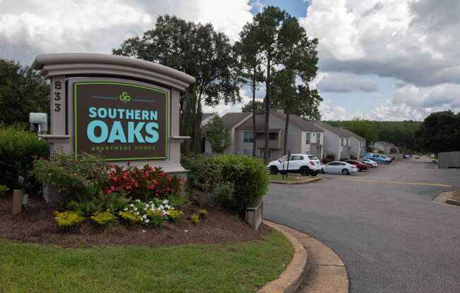 a sign for southern oaks apartments with a parking lot in the background