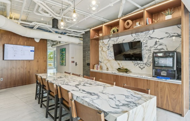 a long marble table with chairs in a room with a tv at Link Apartments® H Street, Washington, 20002