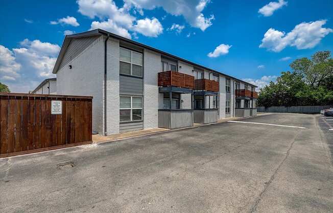 a large white building with a wooden fence and a parking lot in front of it