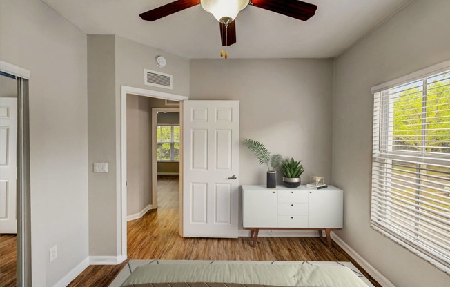 an empty bedroom with a ceiling fan and a white dresser