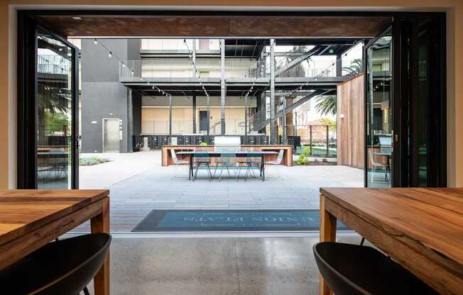 A wooden table is in the foreground of a room with a large open doorway.