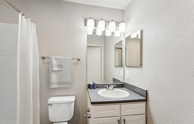 Model Bathroom with White Cabinets, Wood-Style Flooring & Shower/Tub at Lake Cameron Apartments located in Apex, NC.