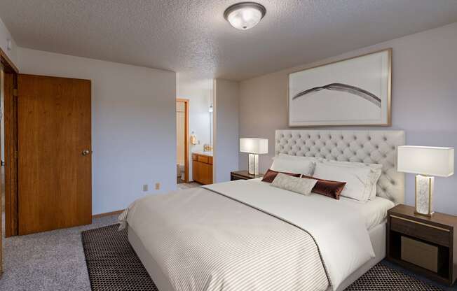 a bedroom with a large bed and a door to a bathroom. Fargo, ND Crescent Park Apartments