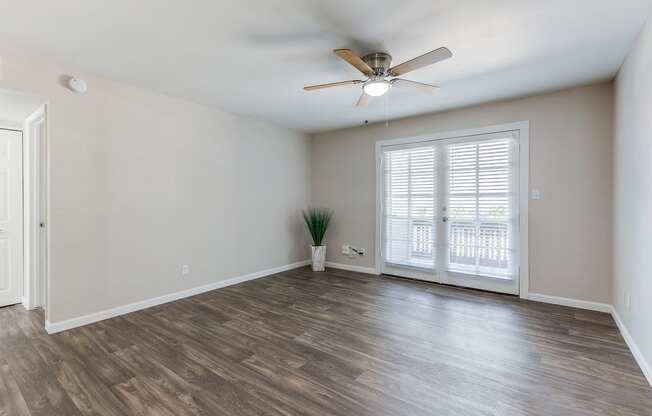 an empty living room with a ceiling fan and a window