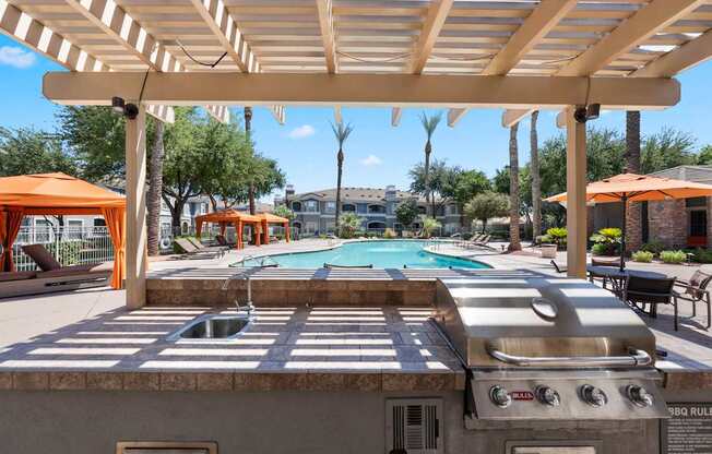 A pool area with a grill and umbrellas.