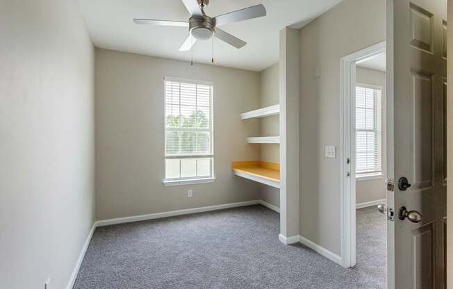 A room with a window, a bench, and a ceiling fan.