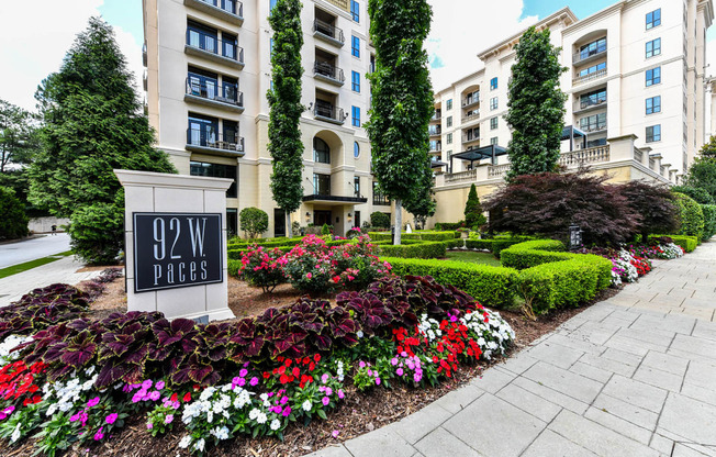 an apartment building with a sign and flowers in front of it