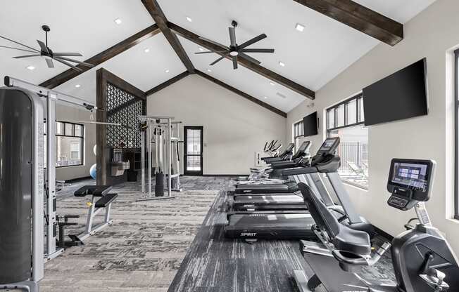 a gym with treadmills and weights and a tv