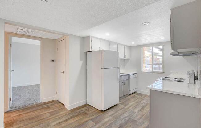 A kitchen with a white fridge and wooden floors.